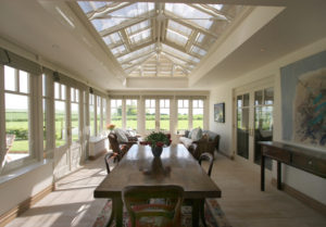Traditional hardwood orangery with plant on bars central refectory table, bright and sunny